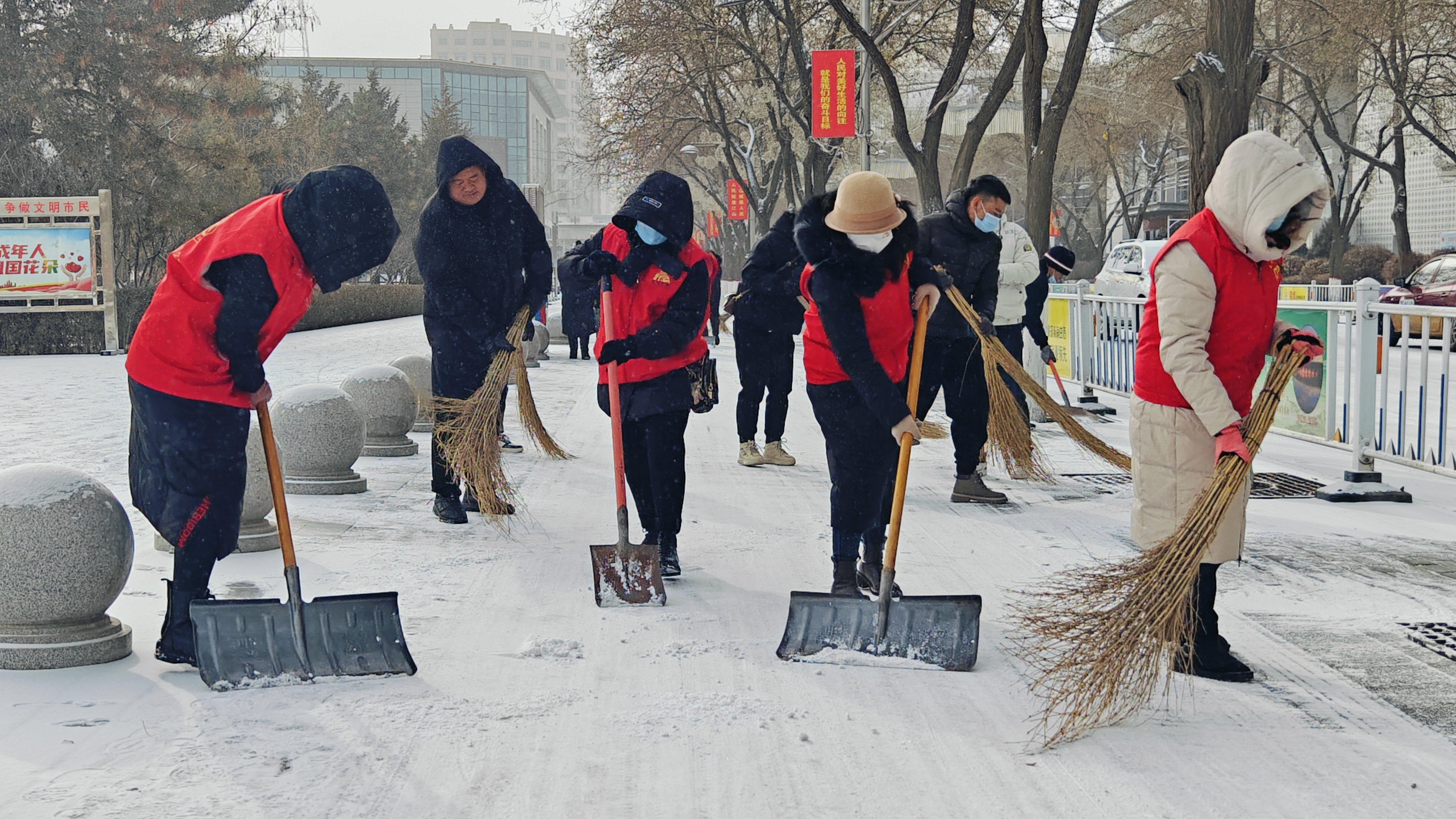 活动中,社区工作人员和志愿者们拿着铁锹,簸箕等工具来到扫雪责任区域